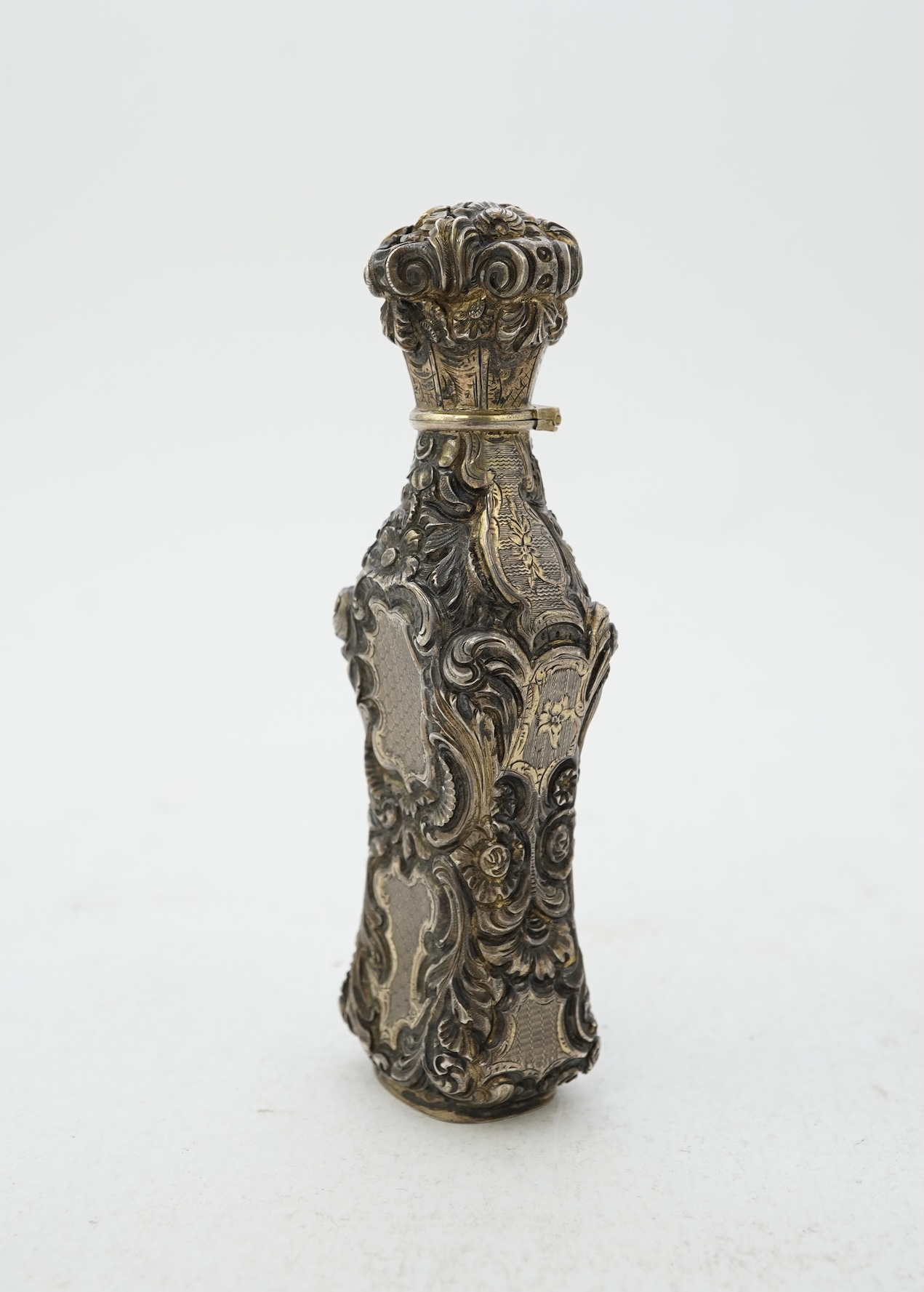 A 19th century French ornate parcel gilt white metal scent flask, with hinged cover and glass stopper